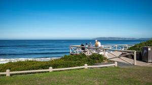 a group of people standing on a boardwalk near the ocean at The Dunes Haven studio in Keurboomstrand