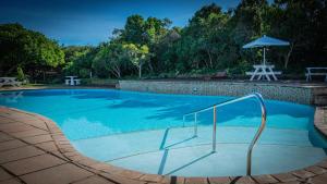 a swimming pool with an umbrella and a table at The Dunes Haven studio in Keurboomstrand