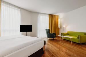 a hotel room with a bed and a green couch at Grimm´s Berlin Potsdam in Teltow