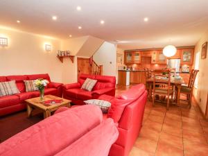 a living room with red couches and a kitchen at Elm Cottage in Aberfeldy