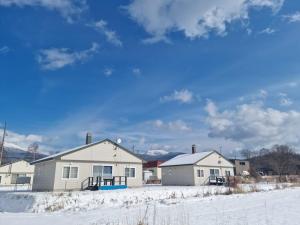 a house in the snow with mountains in the background at Bears Cottages in Furano
