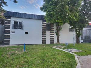 a white building with a tree in the yard at Apartman EC Milica in Stapar