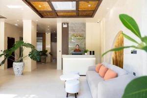 a living room with a couch and a person on a laptop at Sam Hotel & Apartment Da Nang in Danang