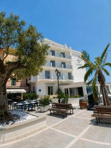 a building with benches and tables and palm trees at Boutique Hotel Alassio in Alassio