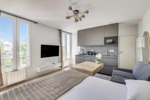 a bedroom with a bed and a living room with a kitchen at Modern Studio 3P - Aubervilliers in Aubervilliers