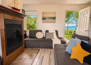 a living room with a couch and a television at Condo 1 - Waterfront with SPA, Fireplace & Barbecue in Sainte-Anne-de-Beaupré