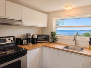 a kitchen with white cabinets and a sink and a window at Condo 1 - Waterfront with SPA, Fireplace & Barbecue in Sainte-Anne-de-Beaupré