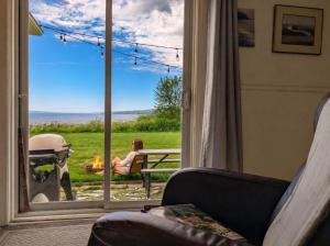 a woman sitting on a bench in front of a window at Condo 1 - Waterfront with SPA, Fireplace & Barbecue in Sainte-Anne-de-Beaupré