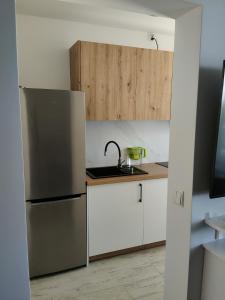 eine Küche mit Edelstahlkühlschrank und weißen Schränken in der Unterkunft APT w centrum in Suwałki
