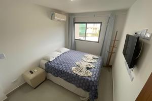 a small bedroom with a bed and a television at Porto bello condomínio in Porto De Galinhas +15 photos