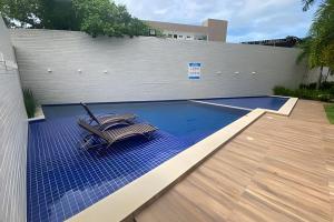 a pool with two chairs sitting on a blue mat at Porto bello condomínio in Porto De Galinhas