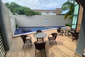a patio with tables and chairs and a pool at Porto bello condomínio in Porto De Galinhas