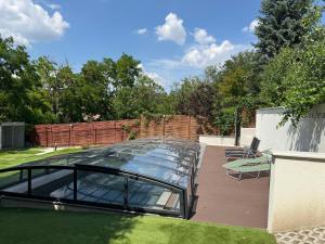 a glassconservatory with chairs and a glass roof at Katica Szállás in Balatonkenese