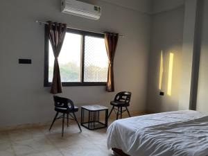 a bedroom with two chairs and a bed and a window at Bhagwati Hotel And Rooms in Udaipur +11 photos