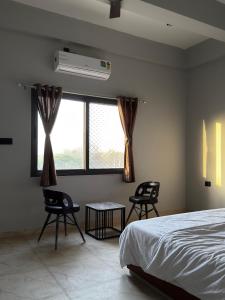 a bedroom with a bed and two chairs and a window at Bhagwati Hotel And Rooms in Udaipur