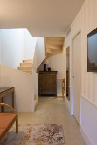 a hallway with white walls and stairs with a television at Hôtel Maison Borrèze in Souillac