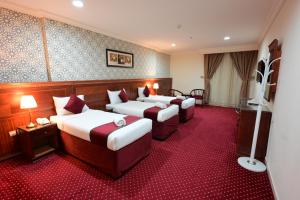 a hotel room with four beds with red carpet at فندق وفاق صدقي in Al ‘Azīzīyah +39 photos