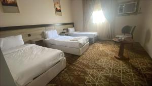 a hotel room with two beds and a chair at اكليل البيت in Al ‘Utaybīyah