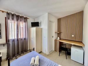 a bedroom with a bed and a desk with a television at Villa Dima in Perissa