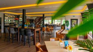 a restaurant with tables and chairs and a bar at Hotel de Harmonie in Giethoorn