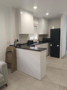 a kitchen with white cabinets and a black refrigerator at Edificio Mañez - Bajo in La Línea de la Concepción