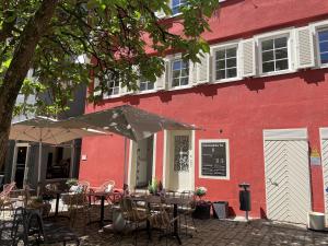 a red building with tables and chairs and an umbrella at Soul Apartment in Aalen