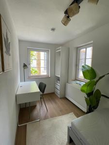 a room with a desk and a table and two windows at Soul Apartment in Aalen