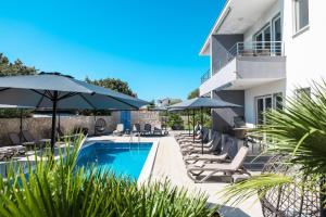 a pool with chairs and umbrellas next to a building at 1oak rentals in Vir