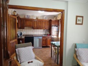 a kitchen with wooden cabinets and a table and a kitchen with a refrigerator at CASA EL CASTAÑÉU in Arriondas