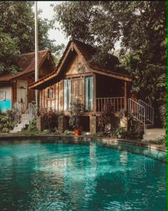 a house with a swimming pool in front of a house at Resort JUNGLEROOM Canggu in Canggu