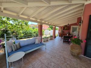 a porch with a blue couch on a patio at Birdsing Cottage in Dassia