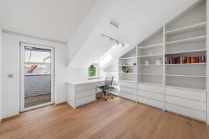 an attic office with white cabinets and a desk at Villa Donau - Sauna & Whirlpool in Vienna
