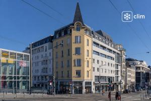 a tall yellow building with a steeple on a city street at Hôtel Nancy Gare-Congrés in Nancy