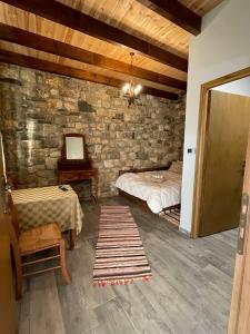 a bedroom with a bed and a stone wall at Villa Lochia - Το Πέτρινο του Θωμά in Rámia