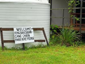a sign sitting on a bench next to a house at Feng Shui Sugarcane Cabin in Proserpine +21 photos