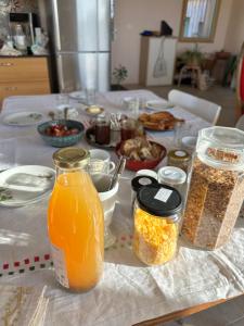 a table topped with jars of orange juice and other food at Les Jardins Vert Framboise yourte et chambres d'hôtes in Beaufour +11 photos