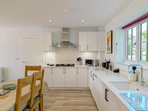 a kitchen with white cabinets and a table and chairs at Wyndham Court - Midhurst in Midhurst