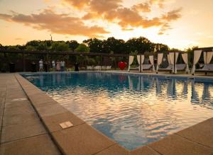 a swimming pool with chairs and a sunset in the background at Casa Vlasia in Snagov