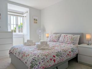 a white bedroom with a bed with a floral bedspread at Wyndham Court - Midhurst in Midhurst