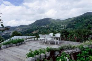 a wooden deck with white chairs on top of a mountain at พอยื้อใจ doichang in Ban Huai Khai