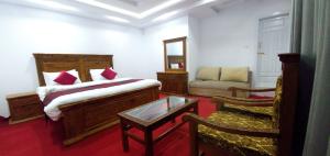 a bedroom with a bed and a couch and a chair at Villaggio Hotel in Khaplu