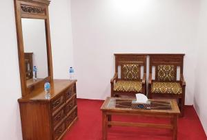 a room with a dresser and a mirror and a table at Villaggio Hotel in Khaplu