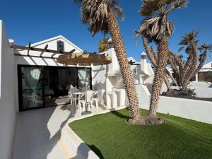 a white house with palm trees and a patio at Casas Lapa in Costa Teguise