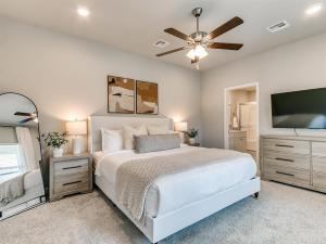 a bedroom with a white bed and a flat screen tv at Spacious Retreat with Vaulted Ceilings & Primary Suite! in Broken Arrow