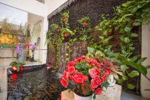 Camila Hotel في مدينة هوشي منه: غرفة بجدار من الطوب مع الزهور والشلال