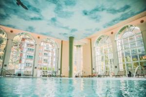 a swimming pool with a mural of clouds on the ceiling at Chalet Regenbogen Familienapartment mit Indoor-Rutschbahn & Spieloase an der Fussgängerzone in Leukerbad