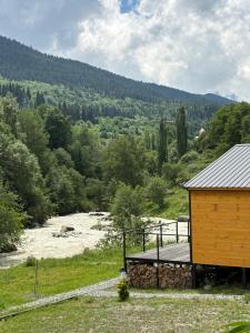 a wooden building on a hill next to a field at Tetnuldi River Chalet in Mestia