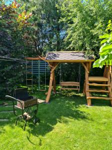 a wooden gazebo with a grill and a swing at Viešnagė Palangoje pas J&I in Palanga