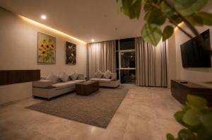 a living room with a couch and a tv at Eliana Hotel in Al Khobar