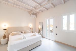 a white bedroom with a large white bed and windows at Drio Kythnos Suites in Dhriopís